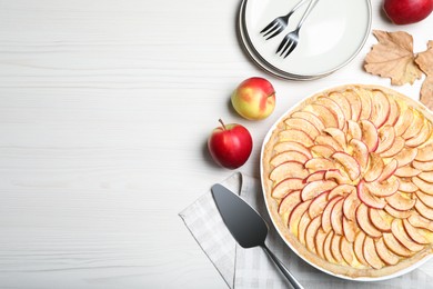 Flat lay composition with tasty apple pie on white wooden table, space for text