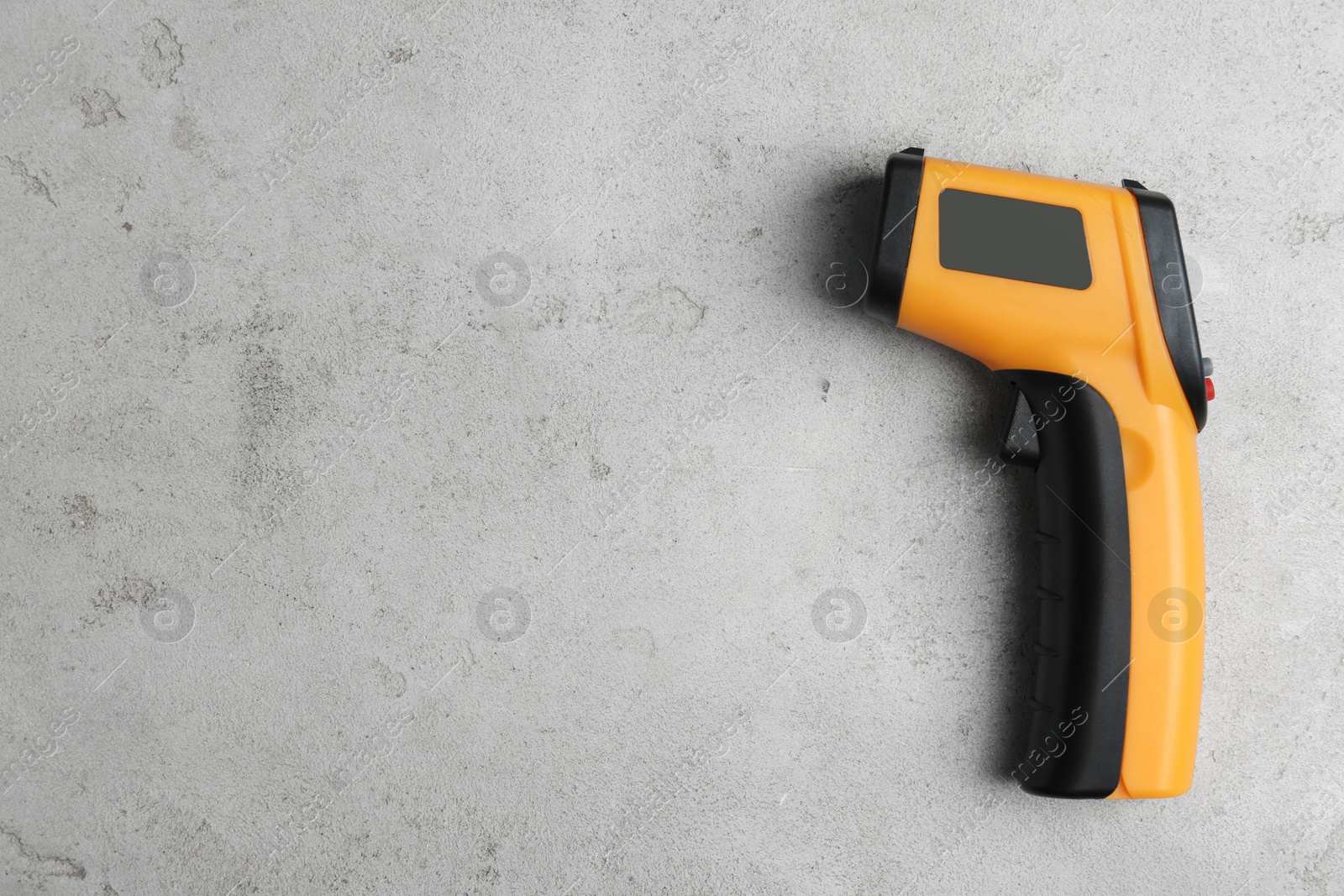 Photo of Modern non-contact infrared thermometer on light grey stone background, top view. Space for text