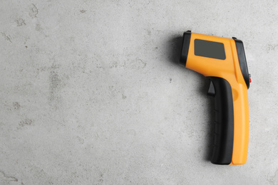 Photo of Modern non-contact infrared thermometer on light grey stone background, top view. Space for text