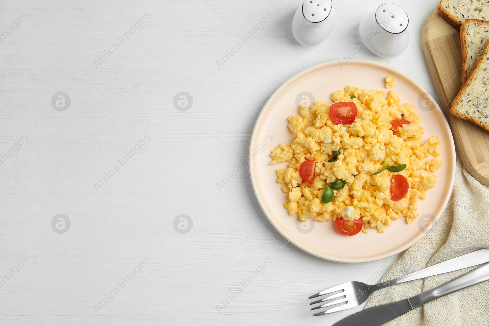 Photo of Tasty scrambled eggs served on white wooden table, flat lay. Space for text