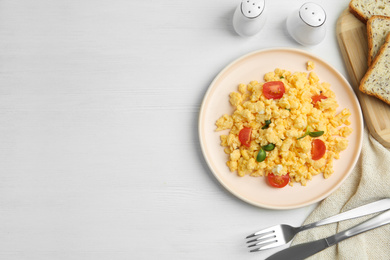 Photo of Tasty scrambled eggs served on white wooden table, flat lay. Space for text