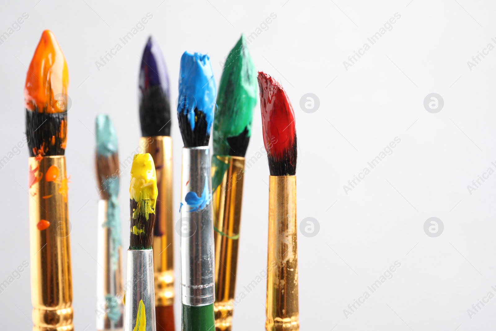 Photo of Brushes with colorful paints on light background, space for text