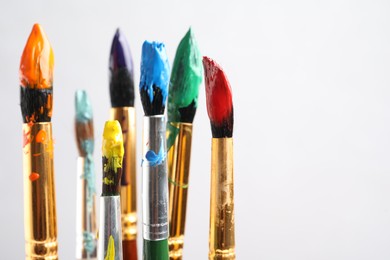 Photo of Brushes with colorful paints on light background, space for text