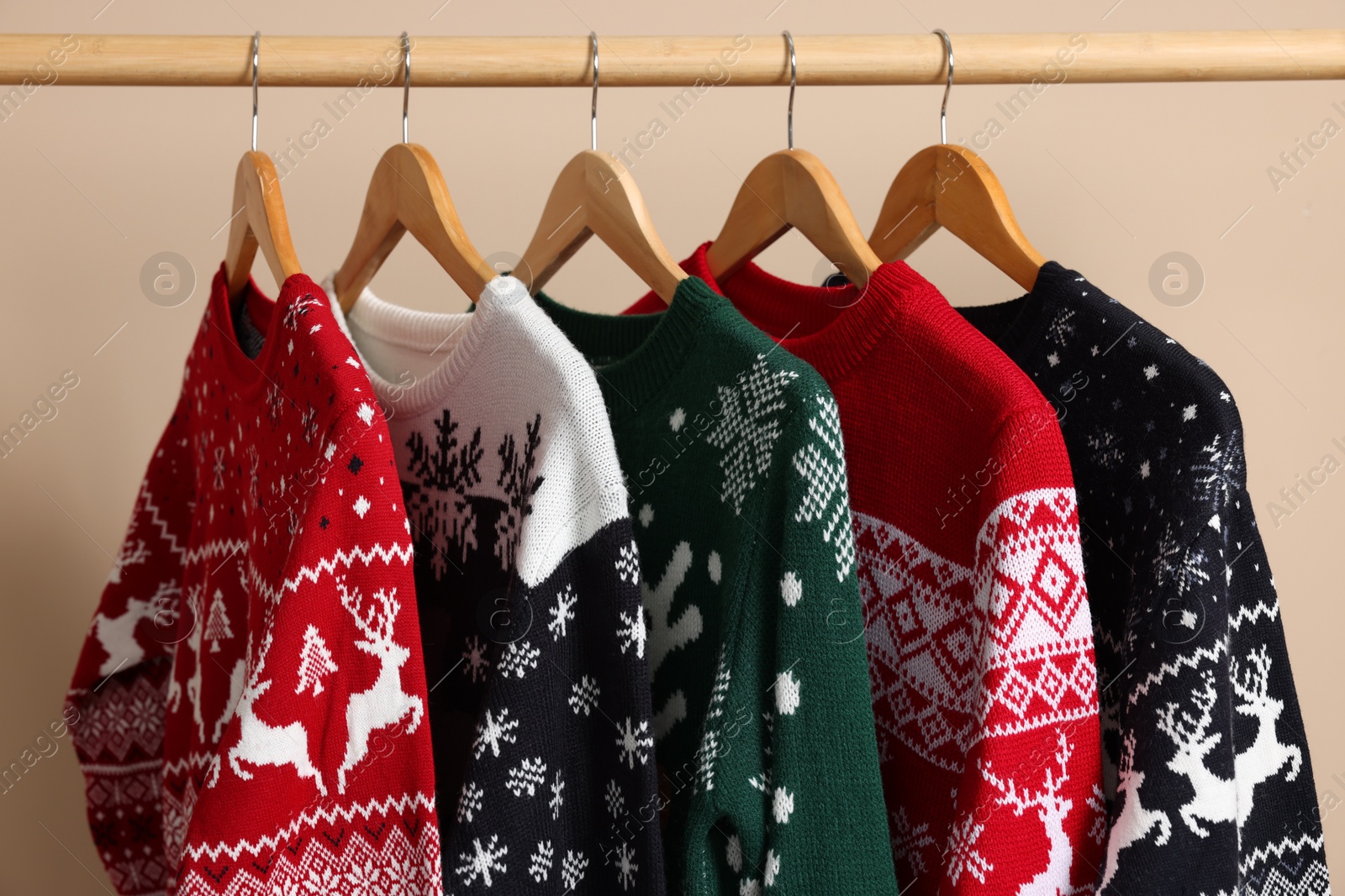Photo of Rack with different Christmas sweaters on beige background