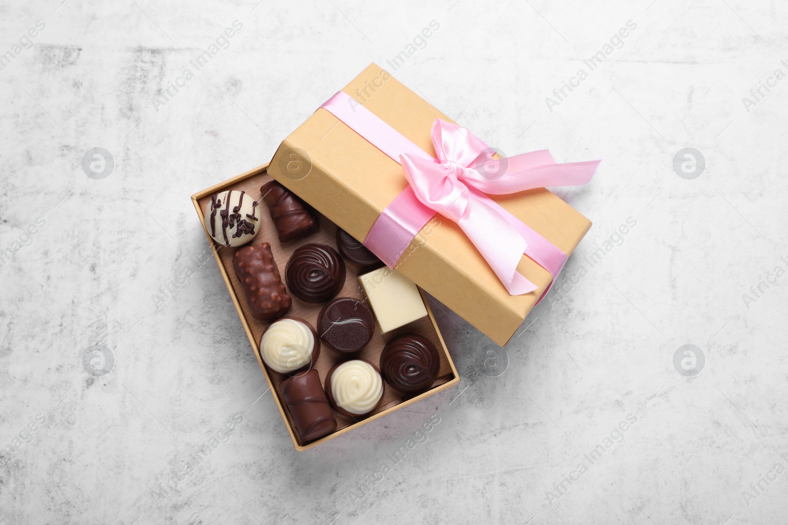 Open box with delicious chocolate candies on white table, top view Photo of Open box with delicious chocolate candies on white table, top view