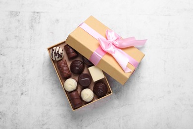 Photo of Open box with delicious chocolate candies on white table, top view