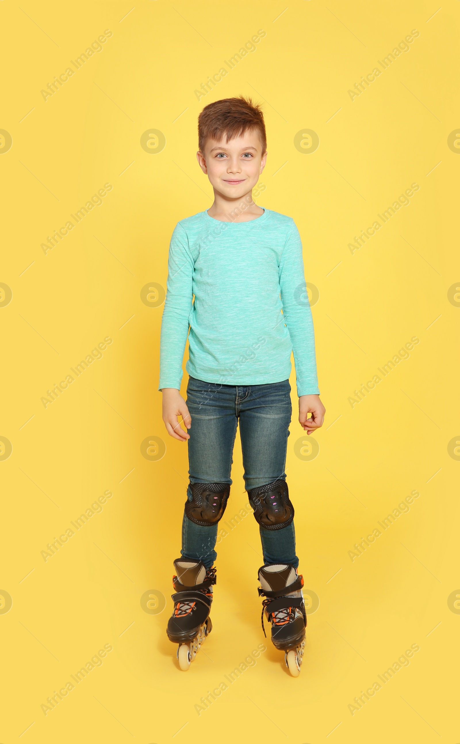 Photo of Full length portrait of boy with inline roller skates on color background