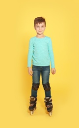 Photo of Full length portrait of boy with inline roller skates on color background