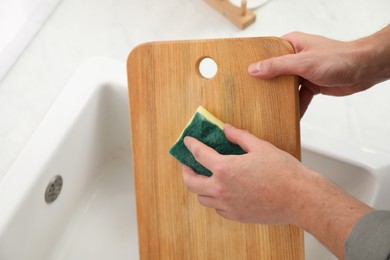 Man washing wooden cutting board in kitchen, closeup