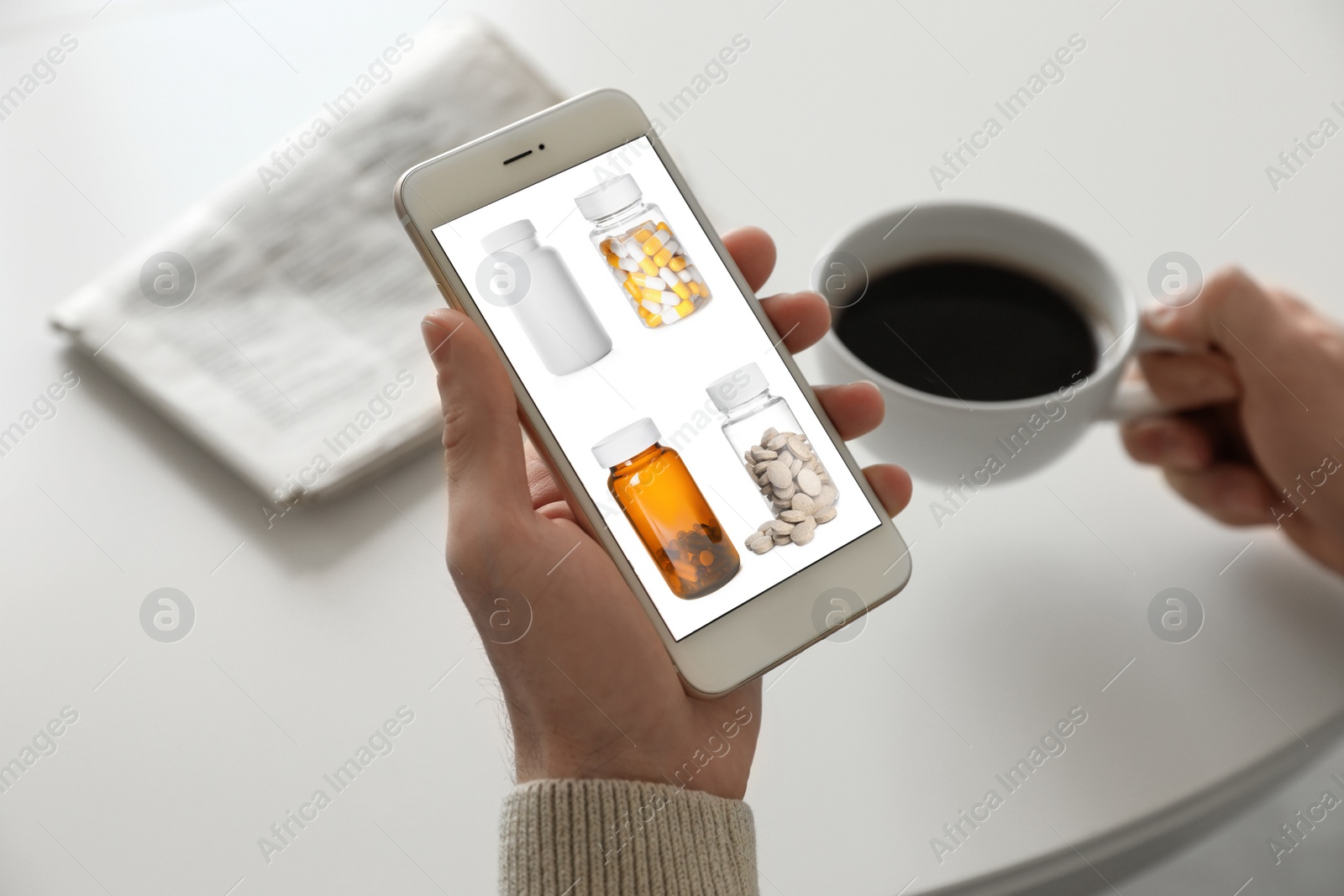 Image of Man with smartphone ordering medications online at table, closeup