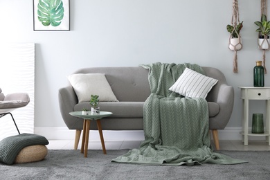 Photo of Soft knitted blanket on sofa in room. Home interior