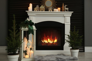Photo of Beautiful Christmas lantern near fireplace in stylish room interior