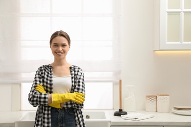 Photo of Happy young woman near countertop with plunger in kitchen