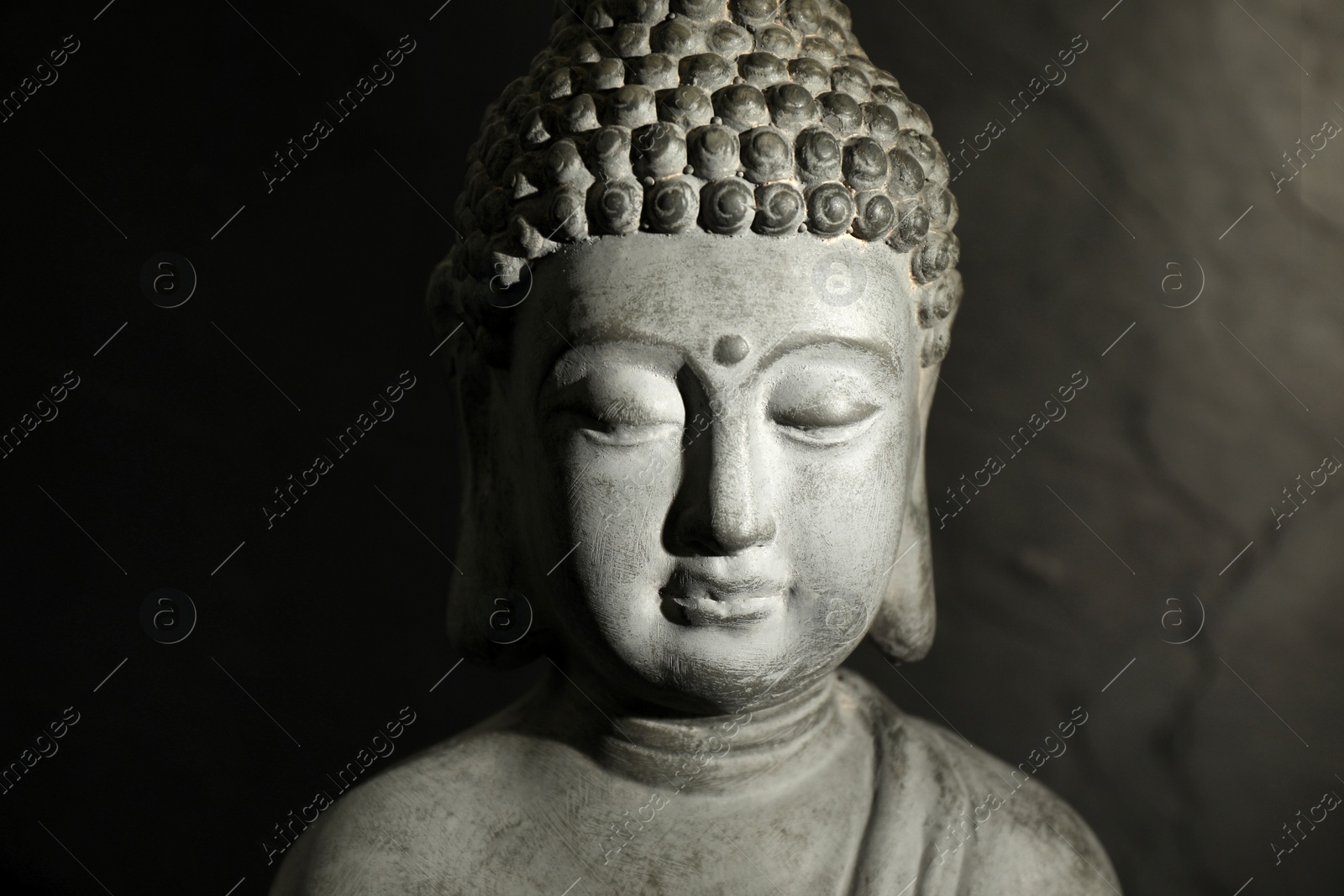 Photo of Buddha statue on dark background, closeup view