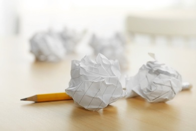 Photo of Sheets of crumpled paper and pencil on wooden table, space for text