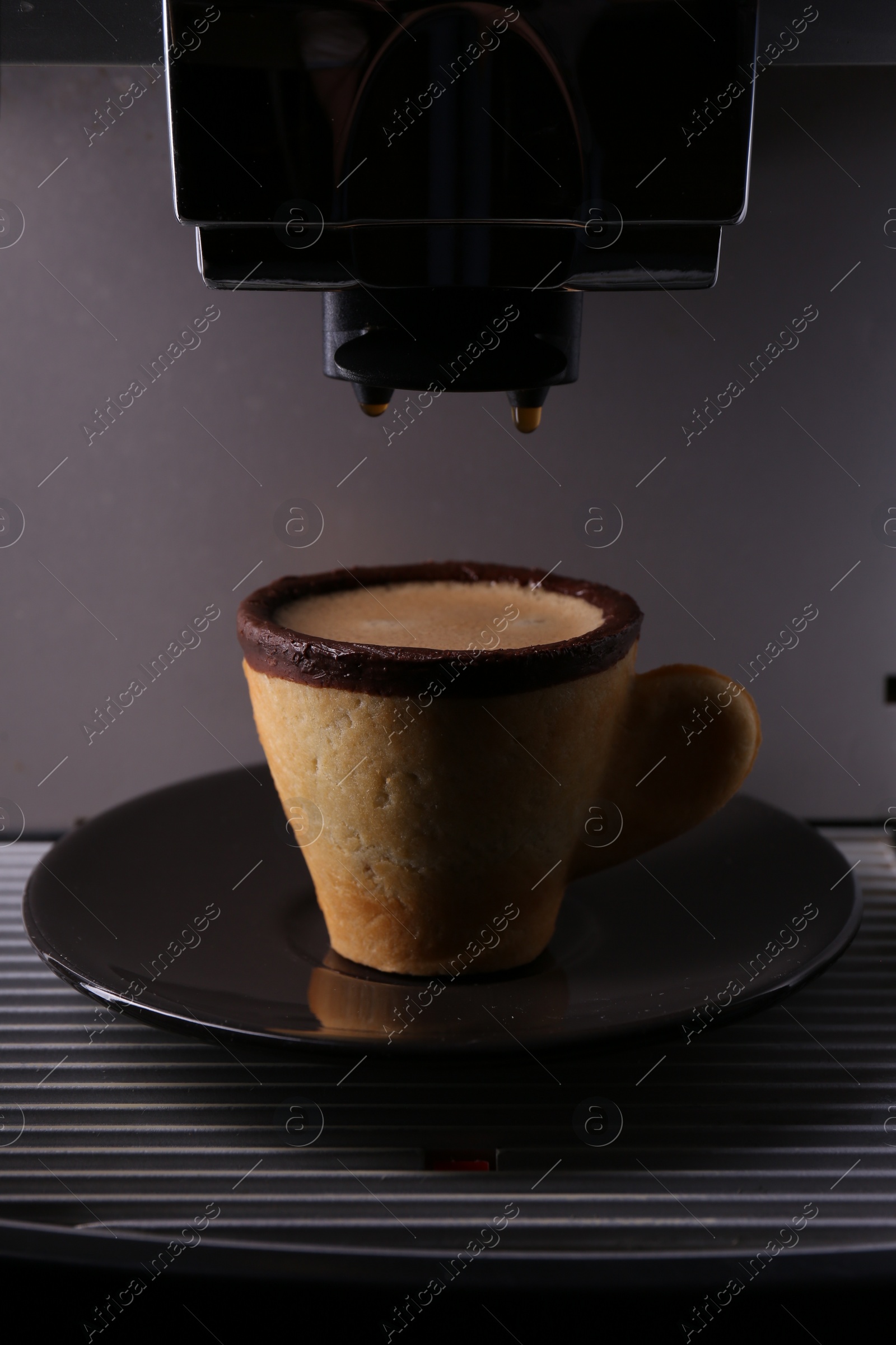 Photo of Coffee machine with delicious edible biscuit cup