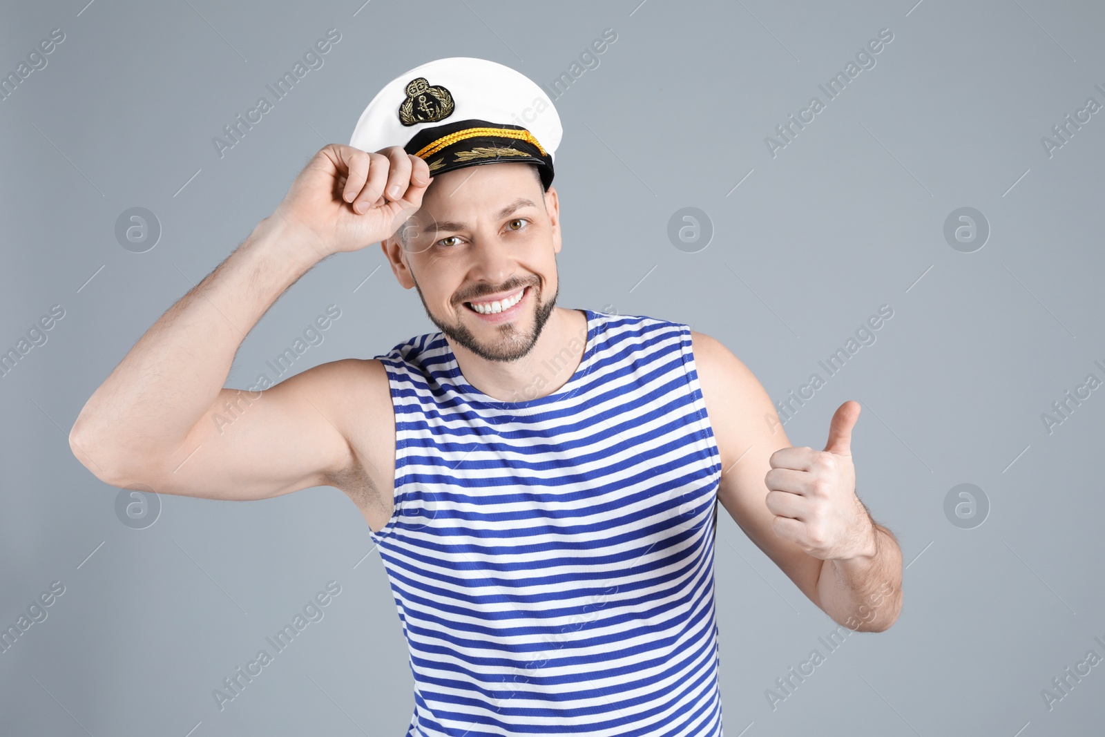 Photo of Happy sailor wearing cap on grey background