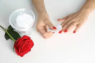 Woman removing nail polish on white background, view from above