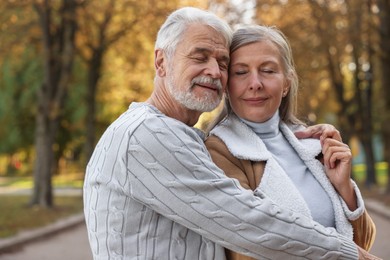 Photo of Portrait of affectionate senior couple in autumn park