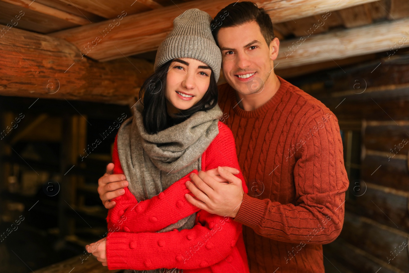 Photo of Lovely couple wearing warm sweaters indoors. Winter season