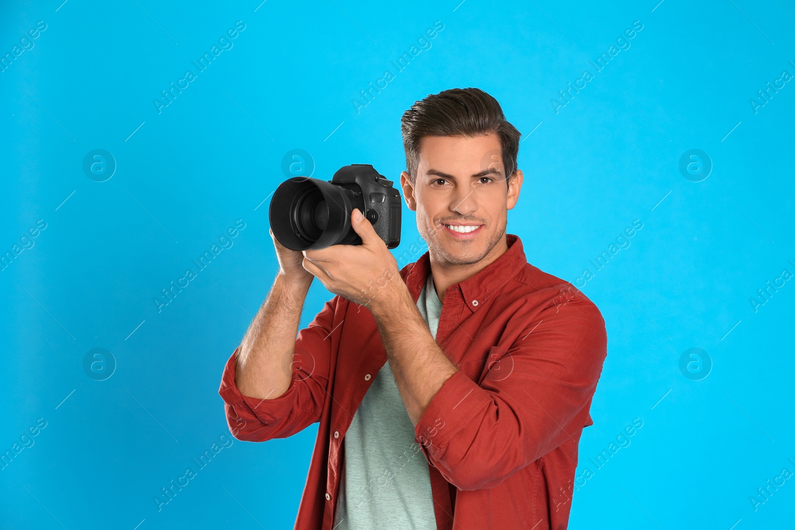 Photo of Professional photographer working on light blue background in studio