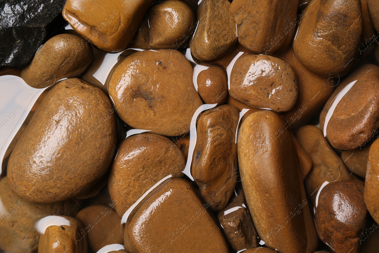 Photo of Beautiful pebbles in water as background, top view