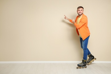 Photo of Young man with roller skates near color wall. Space for text