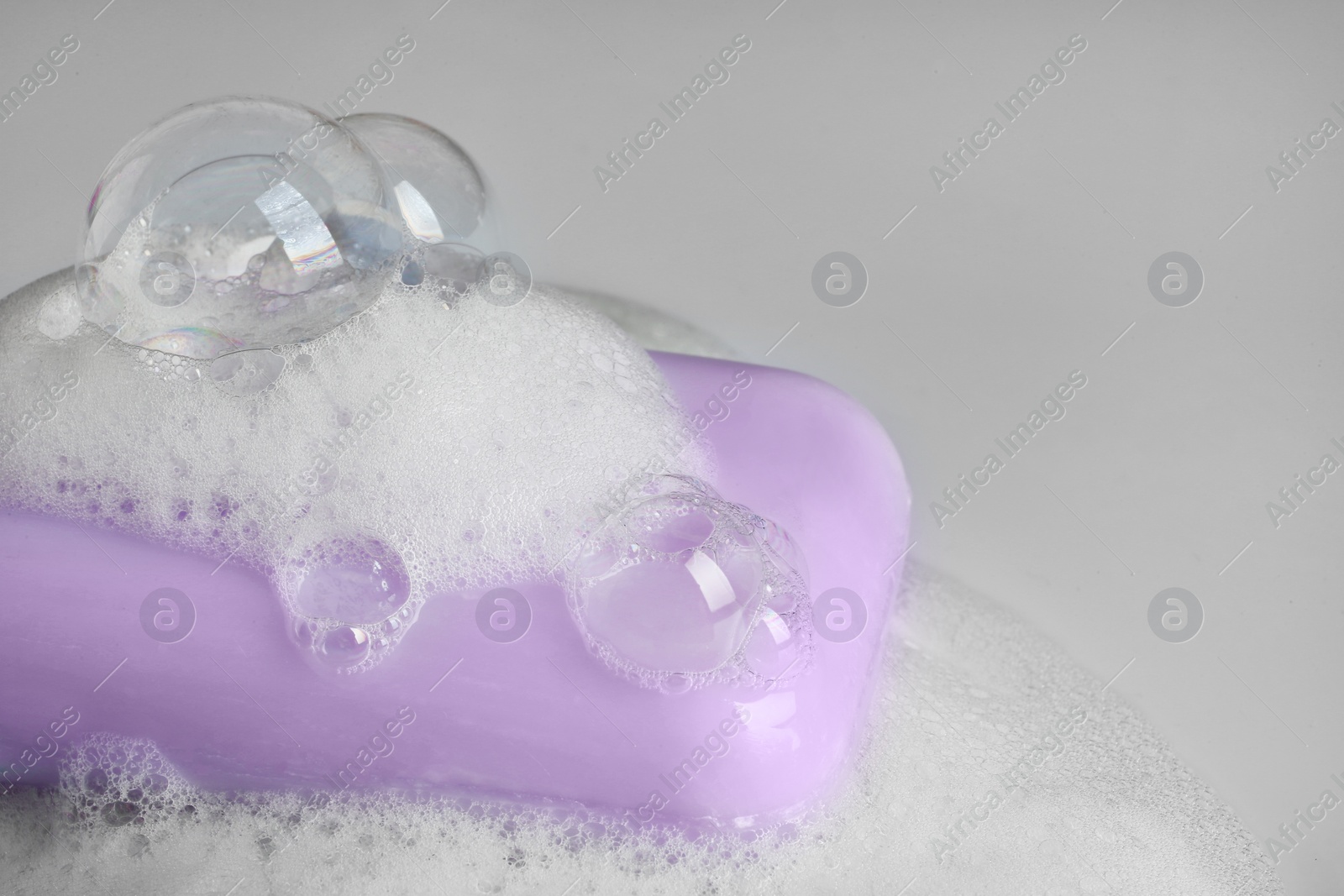 Photo of Soap bar and foam on light background, closeup