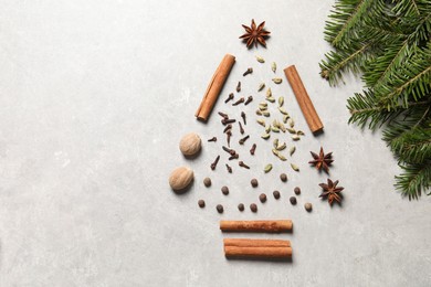 Photo of Christmas tree made of different spices and fir branches on light gray textured table, flat lay. Space for text