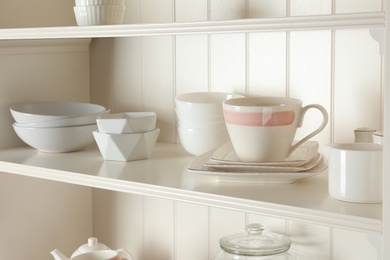 Photo of White shelving unit with set of dishware