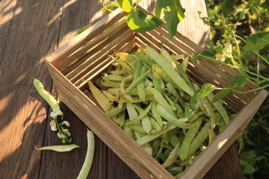 Photo of Crate with fresh green beans on wooden table in garden