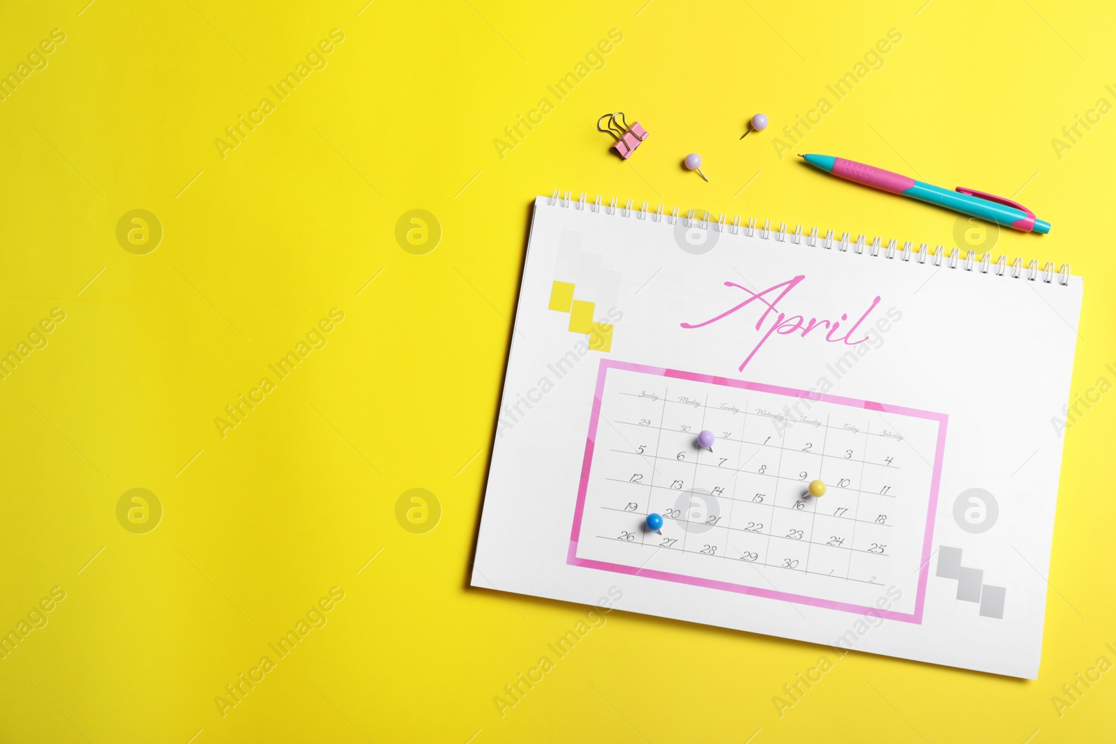 Photo of Calendar page marked with drawing pins on yellow background, flat lay