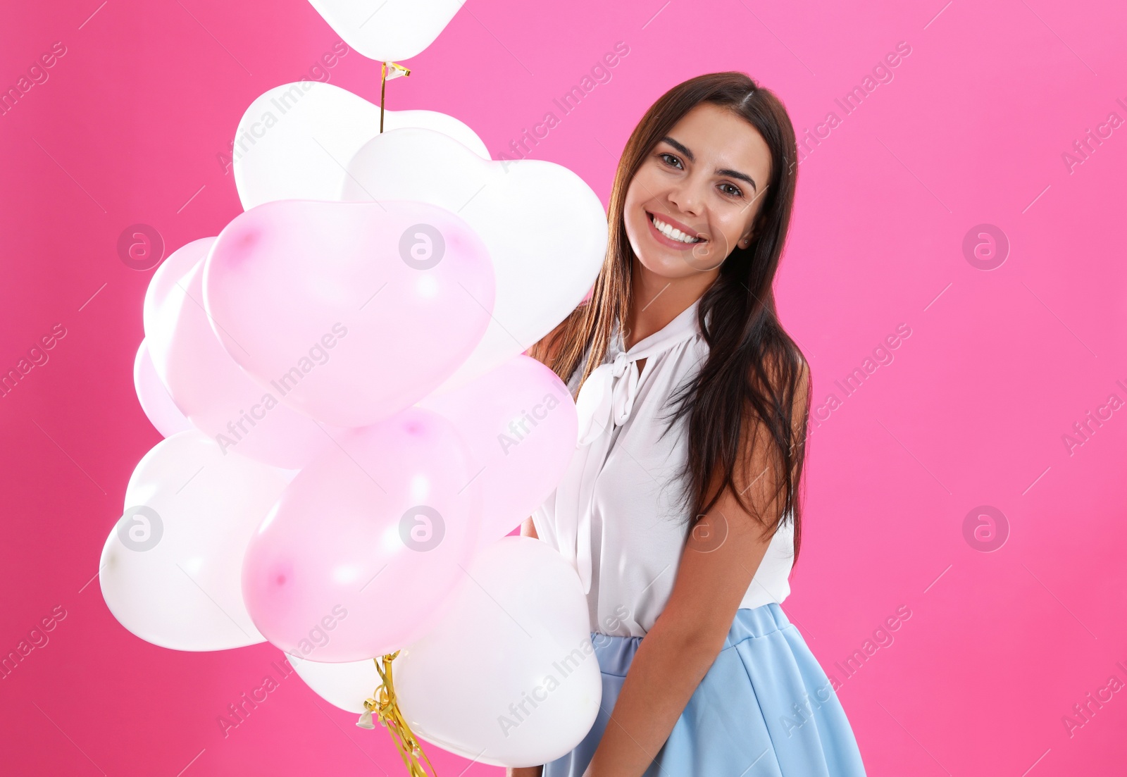 Photo of Young woman with air balloons on pink background. Celebration of Saint Valentine's Day