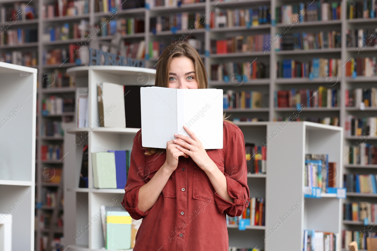 Photo of Young pretty woman with book in library