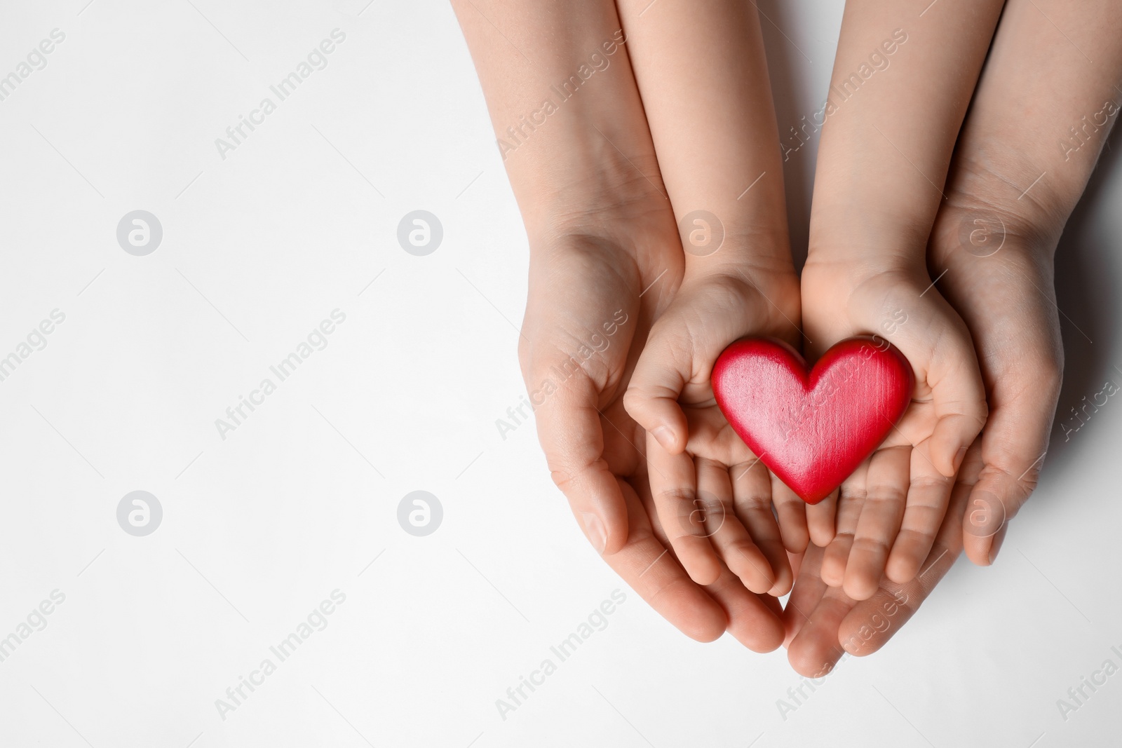 Photo of Woman and kid holding red heart in hands on white background, top view