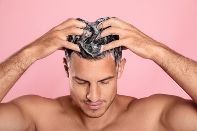 Photo of Handsome man washing hair on pink background