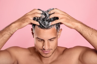 Handsome man washing hair on pink background