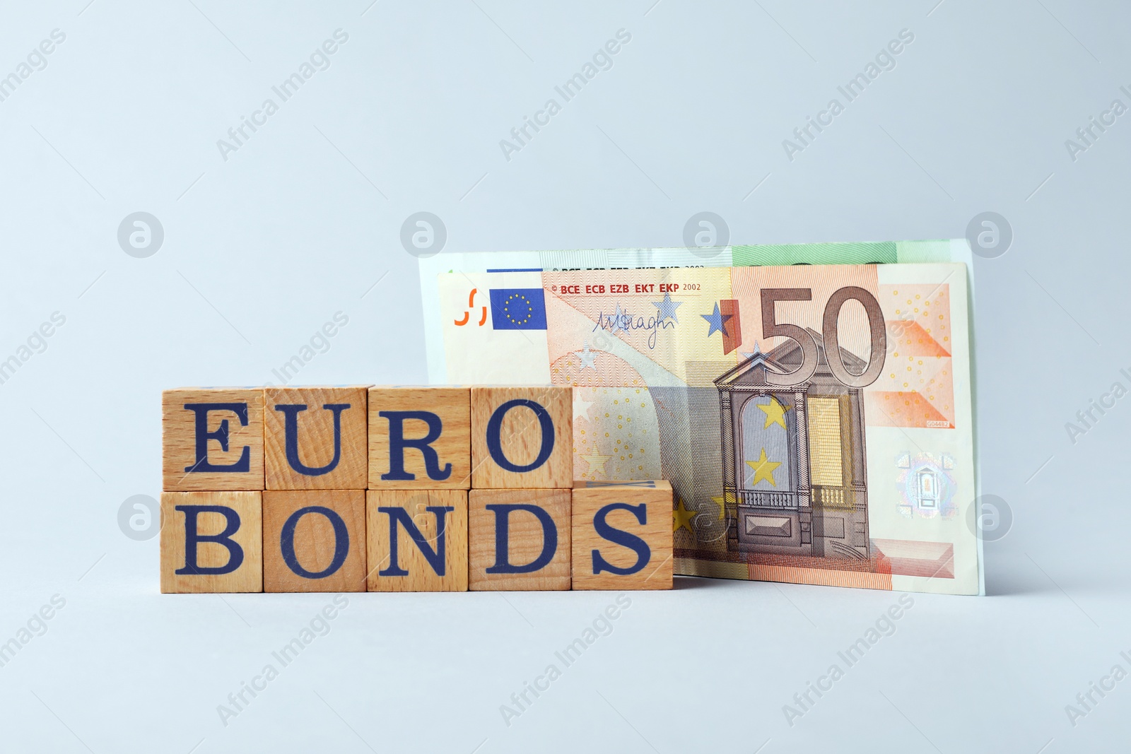 Photo of Word Eurobonds made of wooden cubes with letters and banknotes on light grey background