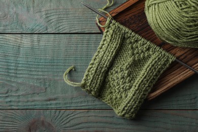 Photo of Soft yarn, knitting and metal needle on light blue wooden table, top view. Space for text