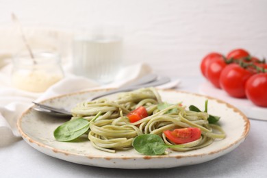 Photo of Tasty pasta with spinach and tomatoes on light table, closeup