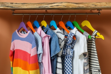 Photo of Rack with different child's clothes near coral wall, closeup