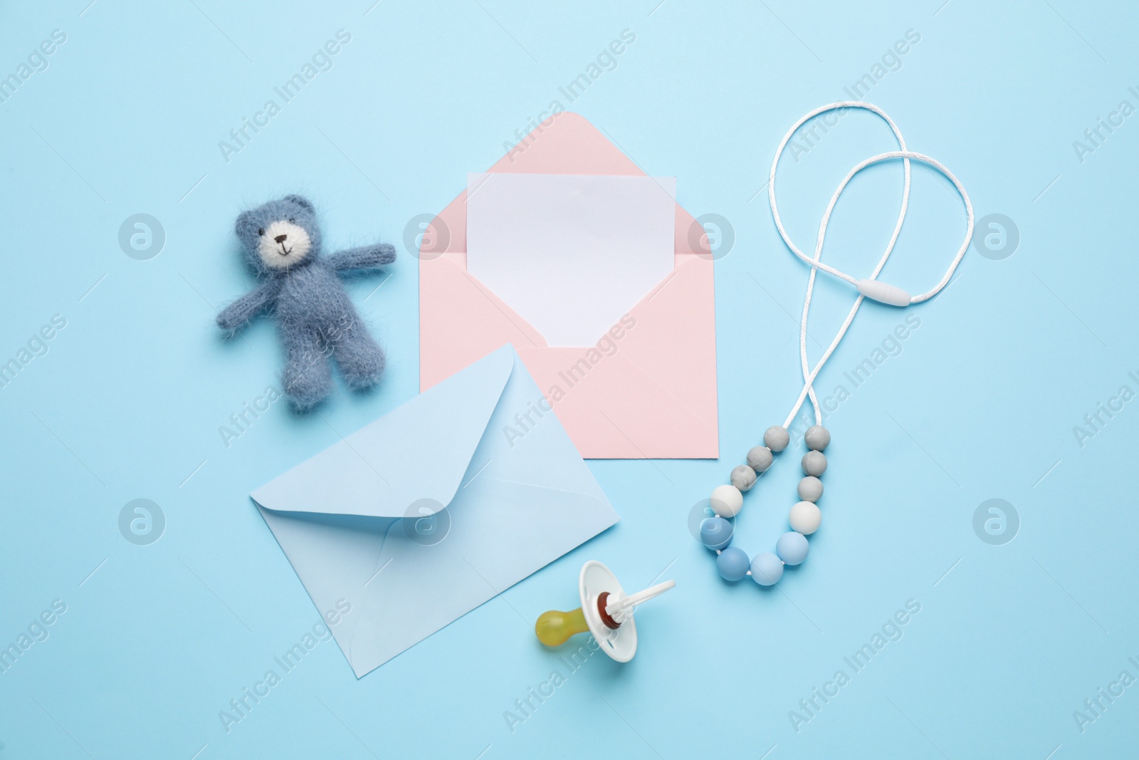 Photo of Envelopes for baby shower and accessories on turquoise background, flat lay