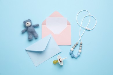 Photo of Envelopes for baby shower and accessories on turquoise background, flat lay