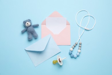 Envelopes for baby shower and accessories on turquoise background, flat lay