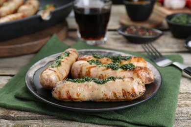 Tasty fresh grilled sausages with sauce on wooden table