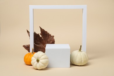 Autumn presentation for product. White geometric figures, pumpkins and dry leaf on beige background