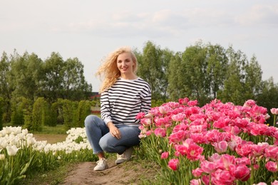 Photo of Happy woman in beautiful tulip field outdoors