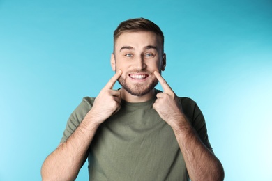 Young man with healthy teeth on color background