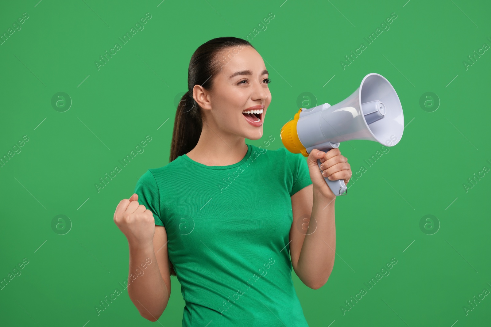 Photo of Happy sports fan using megaphone on green background
