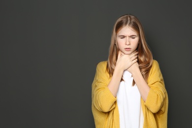 Photo of Teenage girl suffering from cough on dark background. Space for text